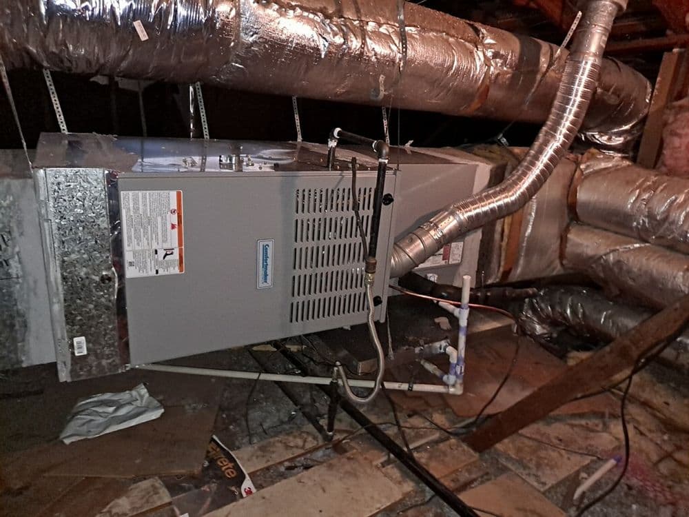 Furnace installation in attic with ductwork and insulation visible. Energy-efficient heating system.