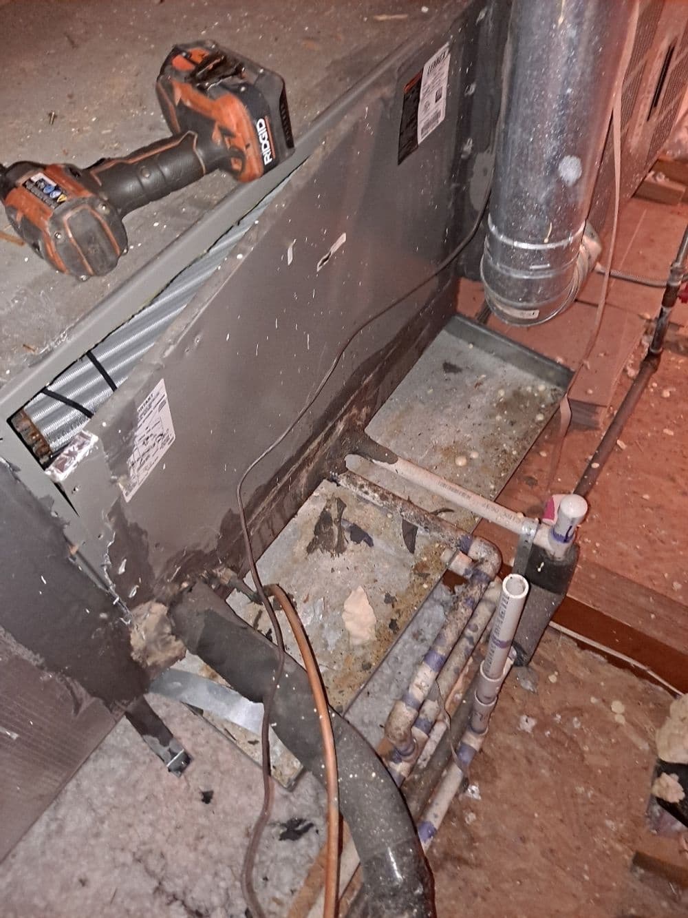 HVAC system with tools, exposed pipes, and debris in a maintenance workspace.