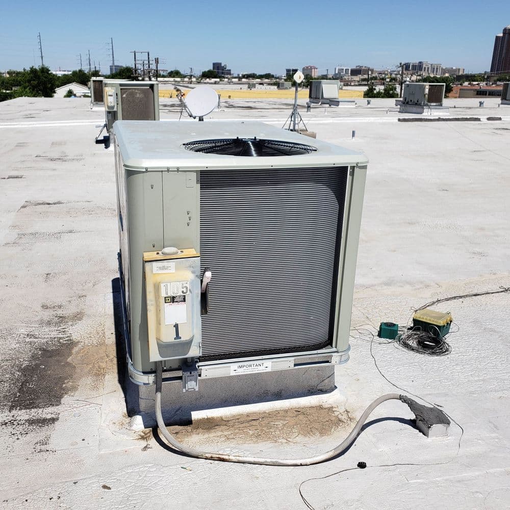 Commercial HVAC unit on a rooftop with urban skyline in the background.