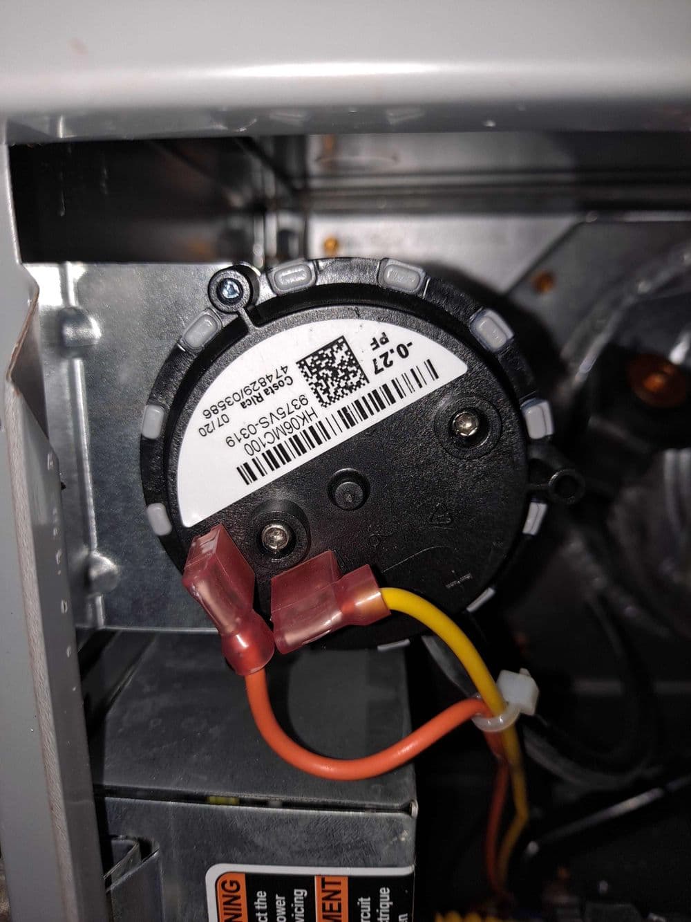 Close-up of a motor component with wiring and label inside an appliance.