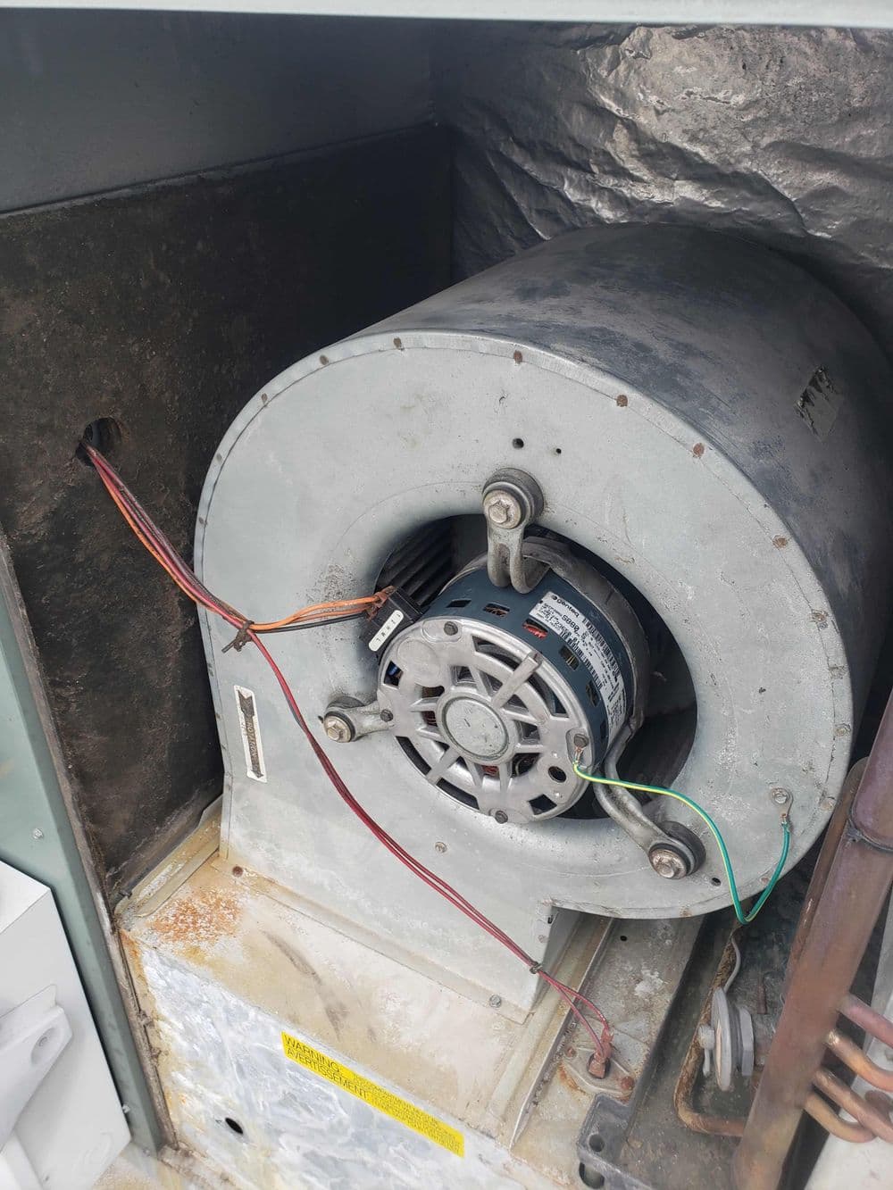 Indoor HVAC blower motor component with visible wiring and metal housing.