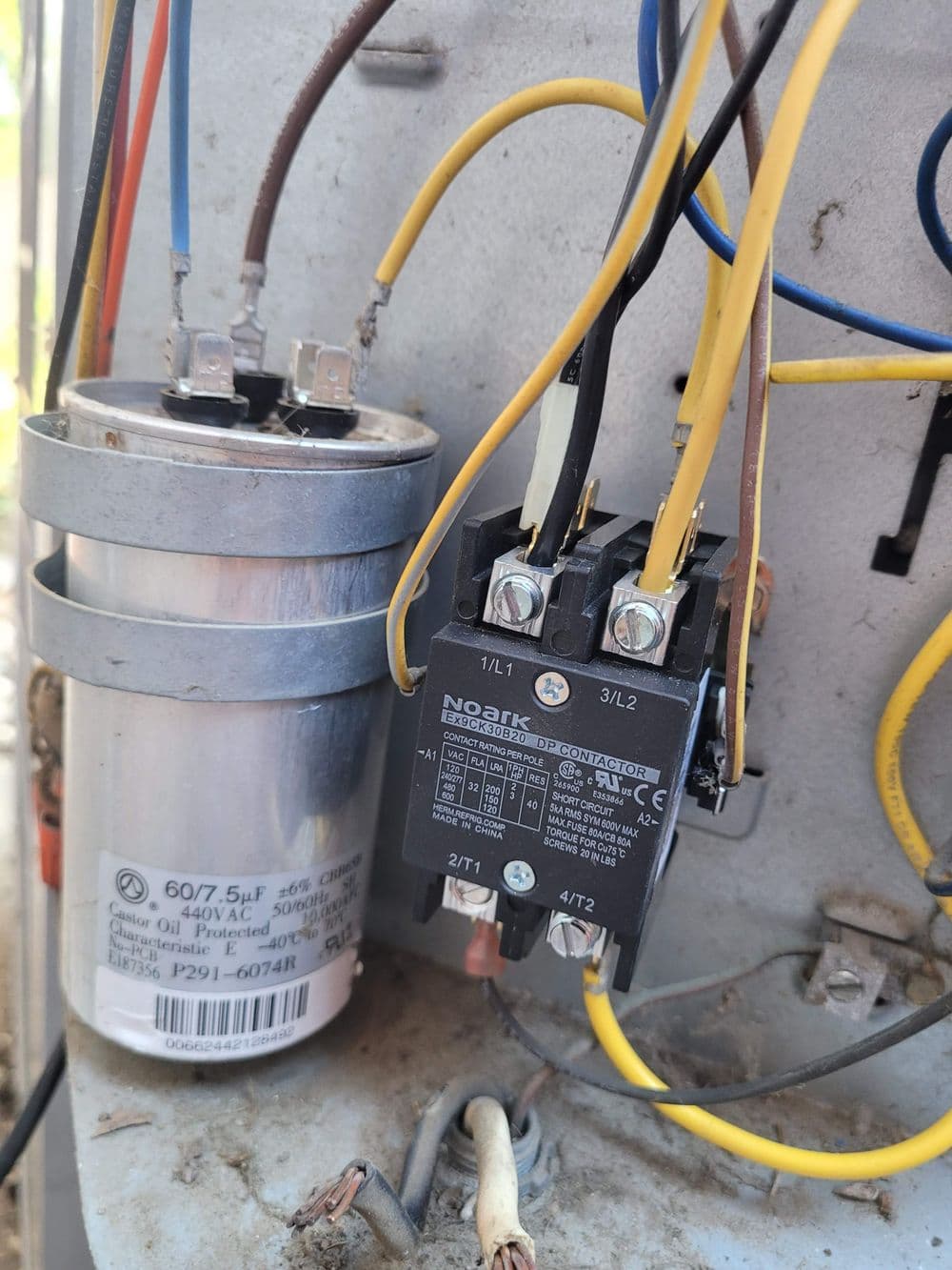 Electrical components including a capacitor and relay on a control panel.