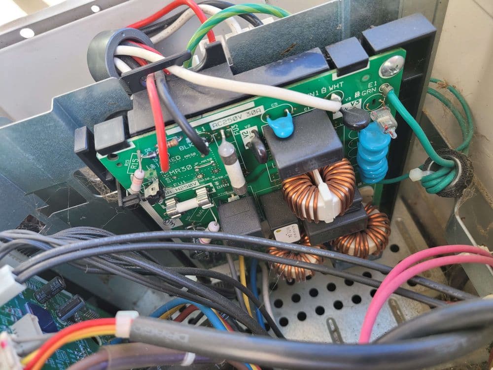 Close-up of electrical circuit board with components and wires inside a machine.