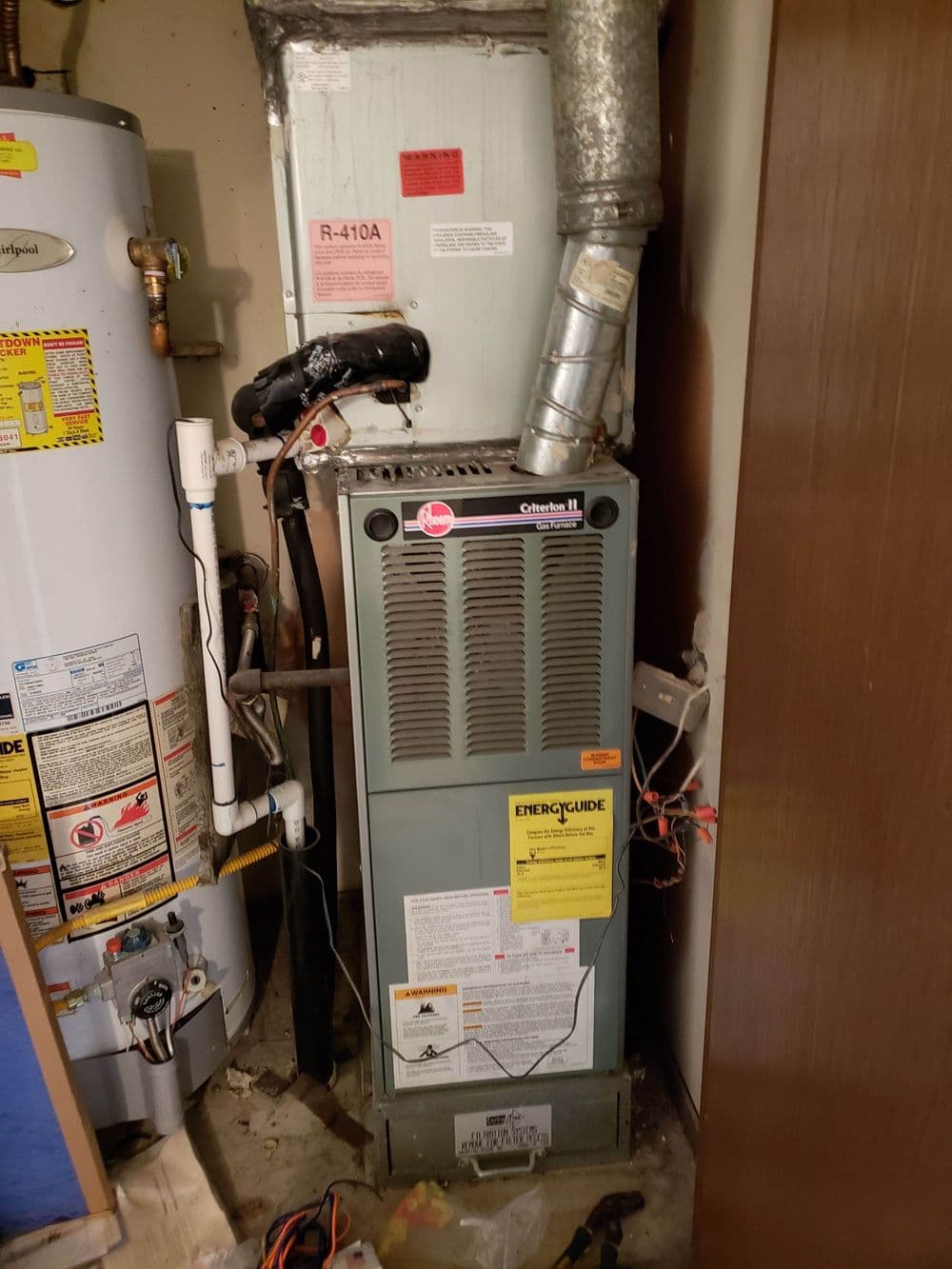 Residential heating system with gas furnace and attached water heater in utility closet.