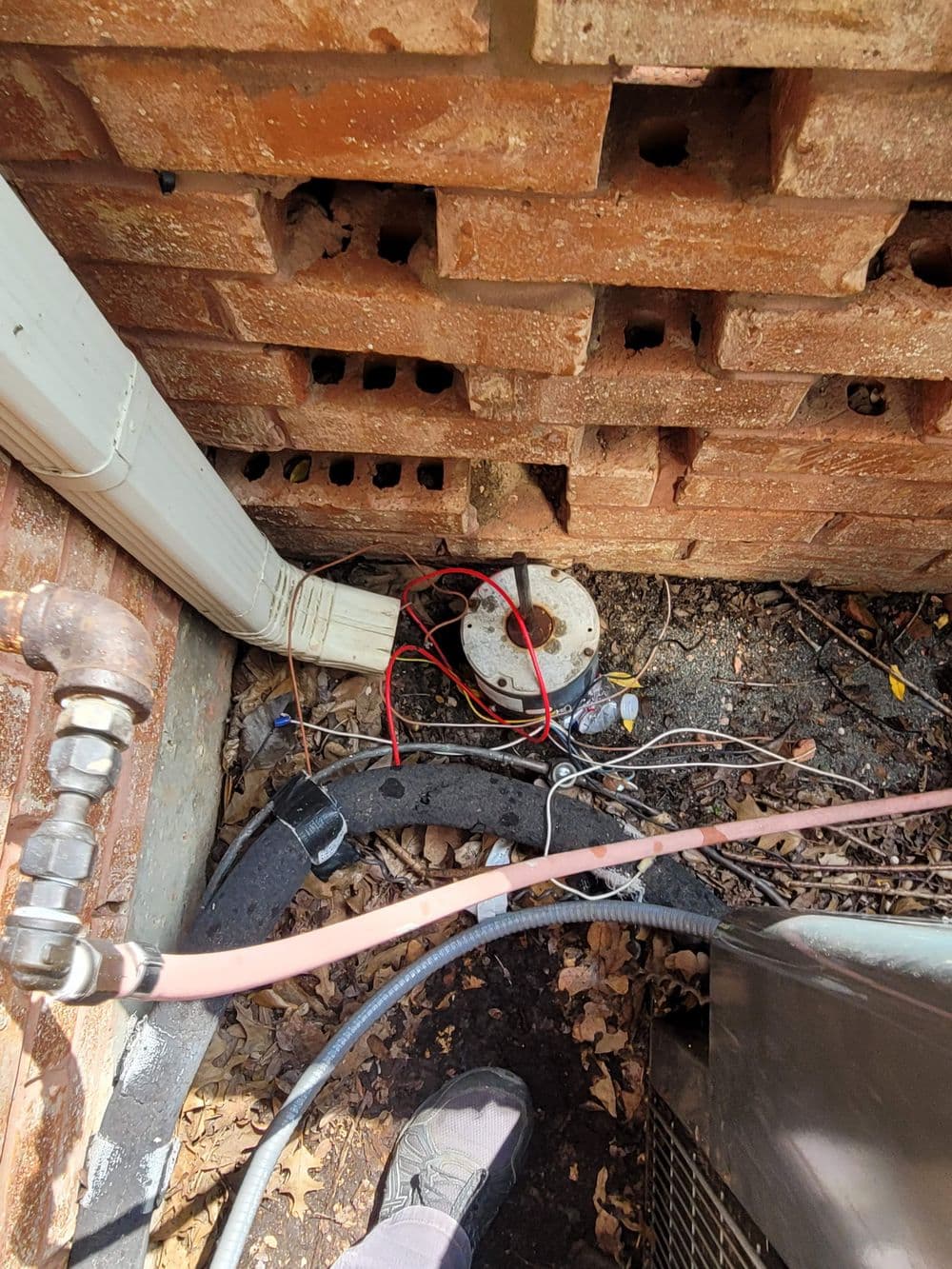 Wiring and pipes near a brick wall, with red wires and utility equipment visible.