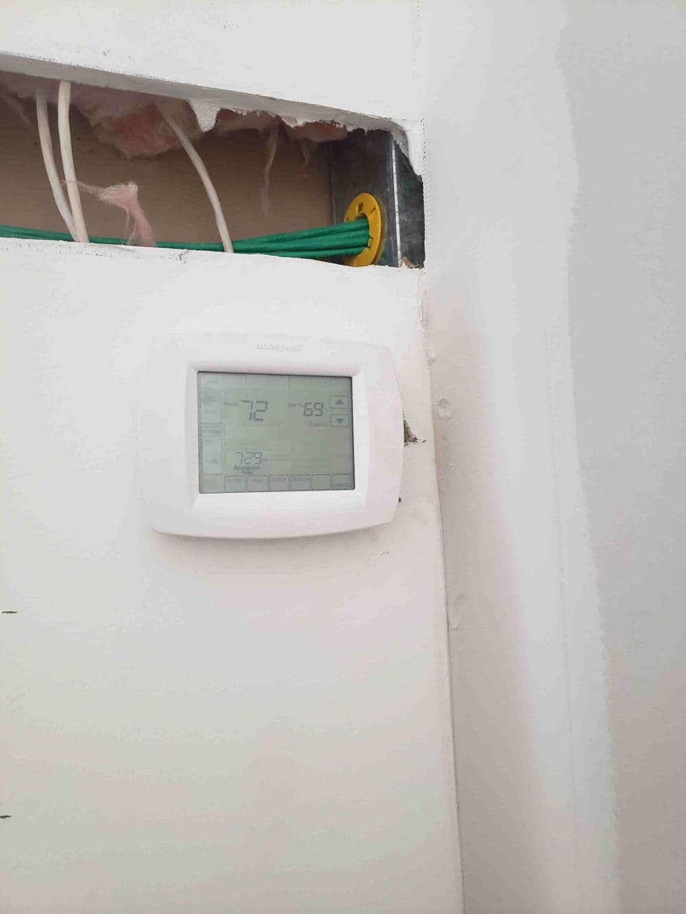 Digital thermostat displaying temperature settings on a wall in a construction zone.