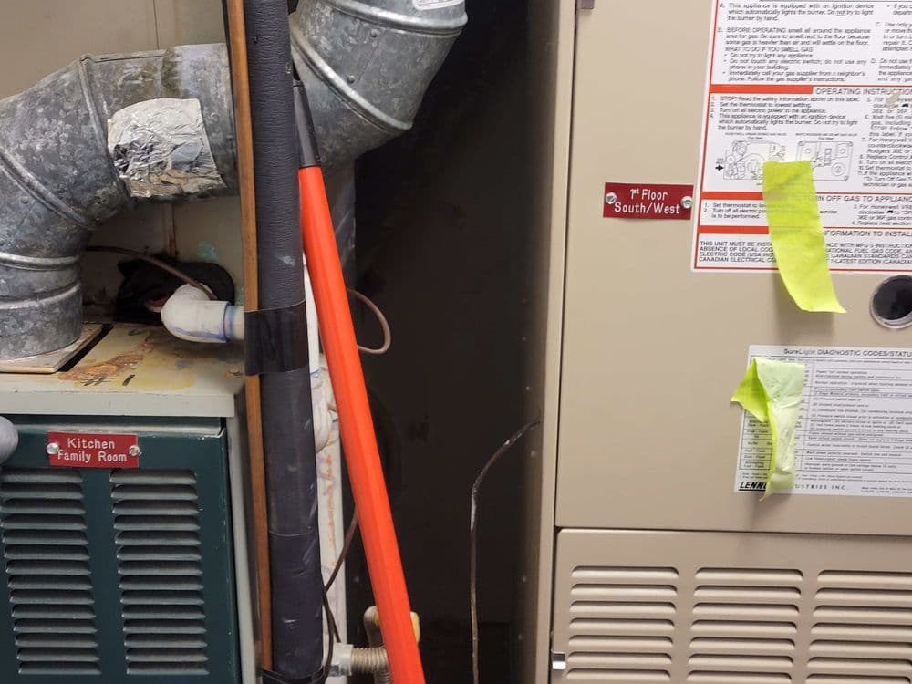 Residential HVAC system with furnace, ductwork, and utility details in a basement setting.